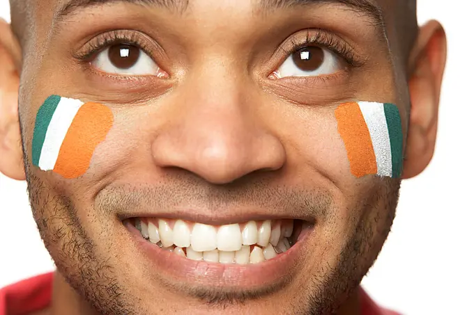 Young Male Sports Fan With Ivory Coast Flag Painted On Face