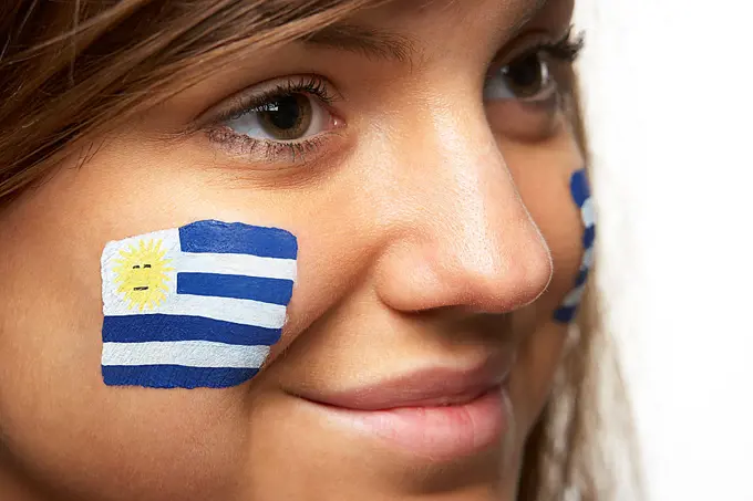 Young Female Sports Fan With Uruguayan Flag Painted On Face