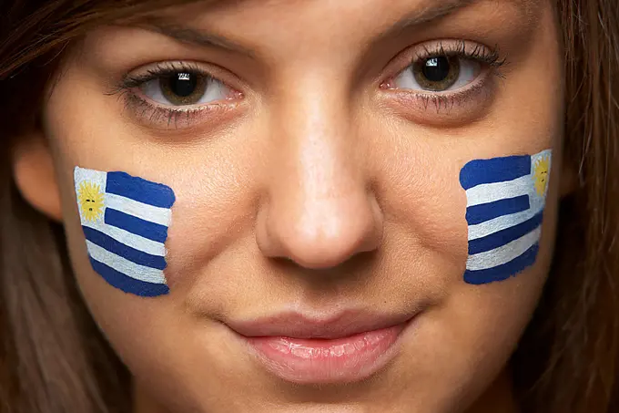 Young Female Sports Fan With Uruguayan Flag Painted On Face