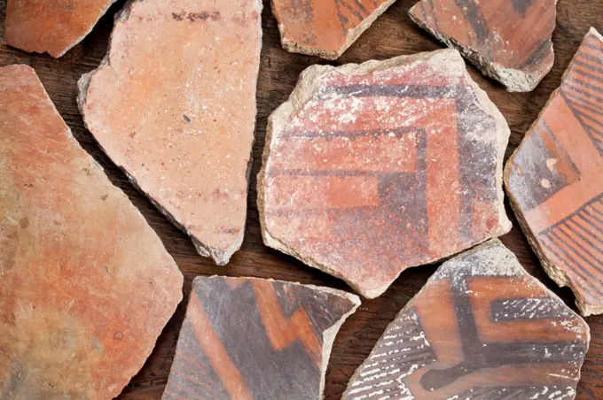 ancient Native American Indian (Anasazi) artifacts, several pottery fragments  on a wood background