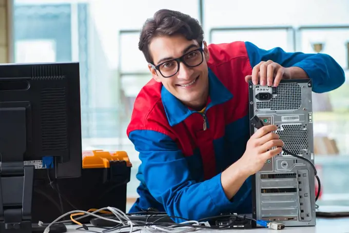 Computer repairman working on repairing computer in IT workshop. The computer repairman working on repairing computer in it workshop