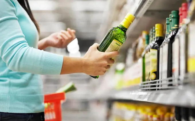 sale, shopping, food, consumerism and people concept - woman buying olive oil at grocery store or supermarket. woman buying olive oil at supermarket or grocery. woman buying olive oil at supermarket or grocery