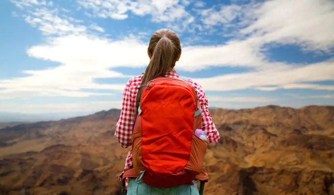 travel, tourism and hike concept - young woman with backpack over grand canyon national park hills background. woman with backpack over grand canyon hills. woman with backpack over grand canyon hills