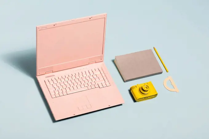 Minimal pastel workspace equipment. Pink laptop, yellow camera, notebook. Millennial lifestyle.. Minimal pastel workspace equipment.