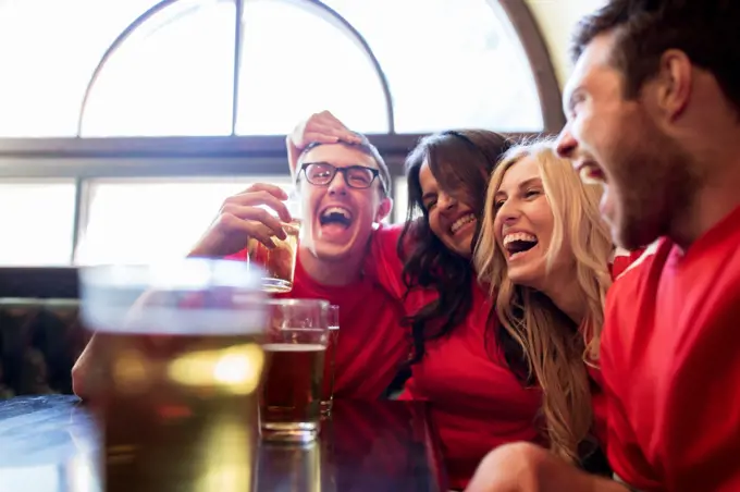 sport, people, leisure, friendship and entertainment concept - happy football fans or friends drinking beer and celebrating victory at bar or pub