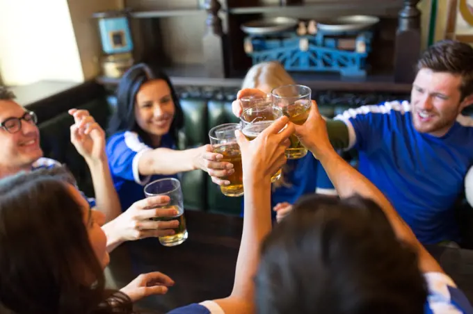 sport, soccer, people and leisure concept - happy friends or football fans clinking beer glasses at bar or pub. football fans clinking beer glasses at sport bar. football fans clinking beer glasses at sport bar