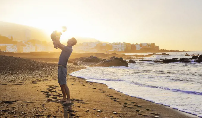 Calm dad posing with baby son over a sunset