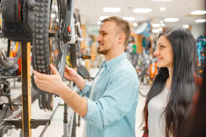 Man checks bicycle disk breaks, shopping in sports shop. Summer season extreme lifestyle, active leisure store, customers buying cycle, couple choosing bikes. Man checks bicycle disk breaks, shopping