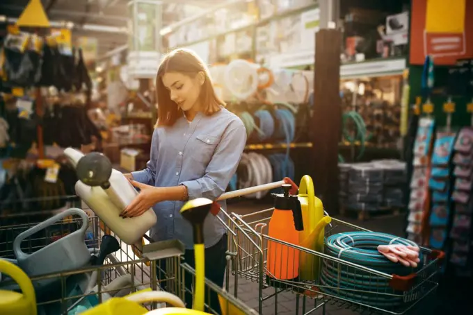 Female buyer choosing gardening tools in shop for gardeners. Woman buying equipment in store for floriculture, florist instrument purchasing. Female buyer choosing tools in shop for gardeners