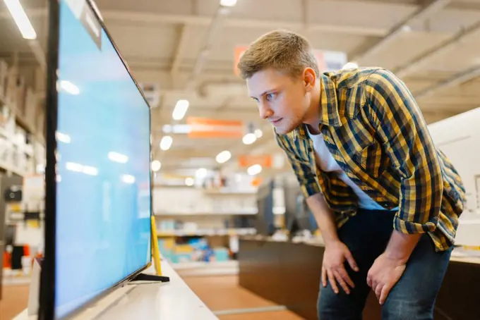 Man choosing TV in electronics store. Male person buying home electrical appliances in market. Man choosing TV in electronics store