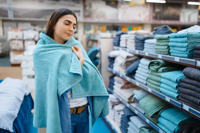 Young woman wrapped herself in a towel, bed linen store. Female person buying home goods in market, lady in bedding shop. Woman wrapped in a towel, bed linen store