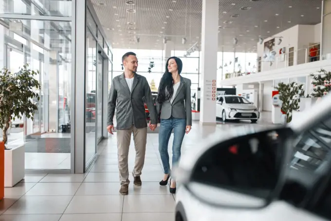 Happy couple buying new car in showroom. Male and female customers choosing vehicle in dealership, automobile sale, auto purchase. Happy couple buying new car in showroom