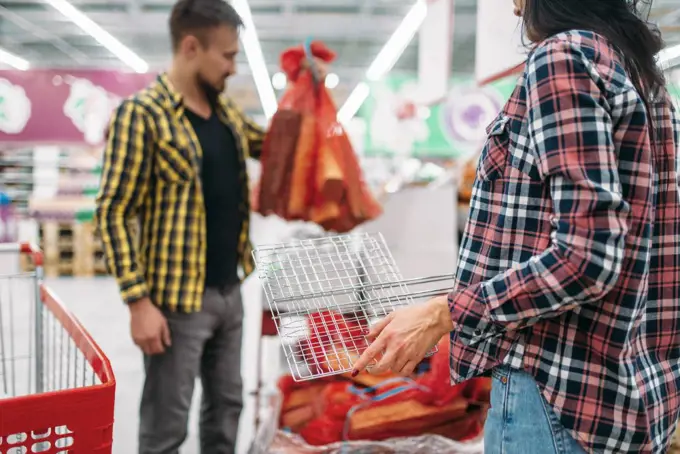 Young couple buying firewood in supermarket. Male and female customers on family shopping. Man and woman purchasing goods for the house. Young couple buying firewood in supermarket