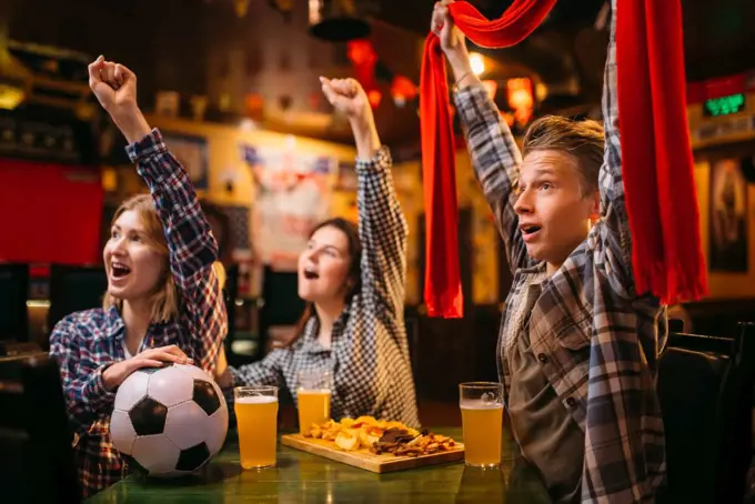 Football fans with scarf watching match and raise their hands up in sports bar. Tv broadcasting, young friends leisures in pub, favorite team wins. Football fans raise their hands up in sports bar