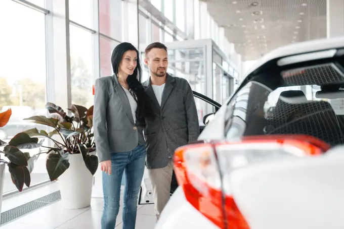 Happy couple buying new car in showroom. Male and female customers choosing vehicle in dealership, automobile sale, auto purchase. Happy couple buying new car in showroom