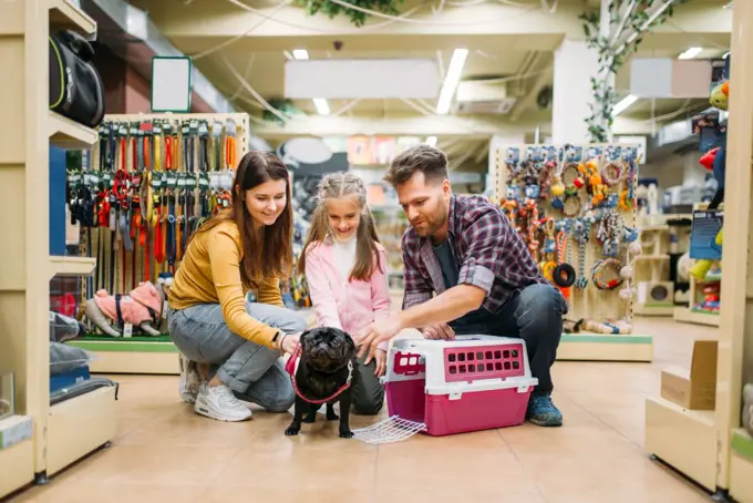 Family buying supplies for little puppy in petshop. Father, mother and dauther chooses accessories for dog in pet shop. Family buying supplies for little puppy in petshop