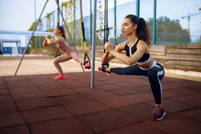 Slim women doing balance exercise on sports ground outdoors, group fitness training. Female athletes in sportswear, team fit workout, teamwork. Slim women doing balance exercise, group training