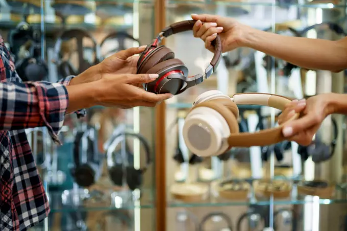 Girl buying headphones in audio store, music fan. Female person in music shop, showcase with earphones on background, buyer in multimedia salon. Girl buying headphones in audio store, music fan