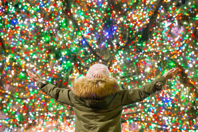 Happy girl on the background of the Rockefeller Christmas tree in New York. Beautiful Christmas Tree at Rockefeller center. Happy girl on the background of the Rockefeller Christmas tree in New York