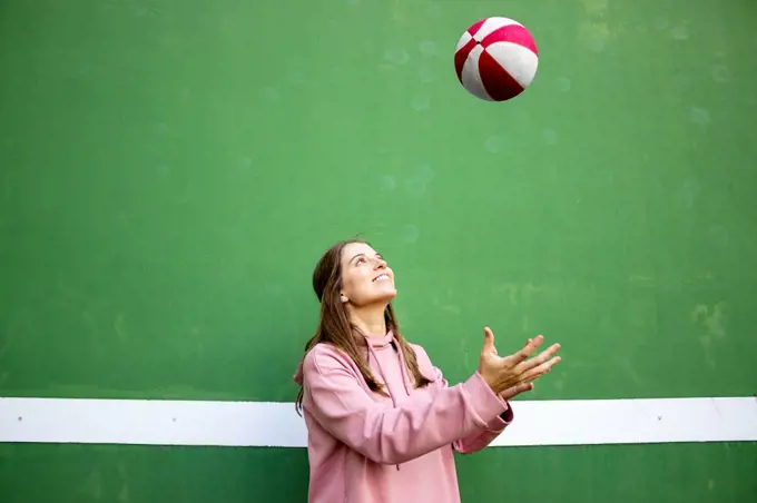 Teenager female playing basketball over green wall