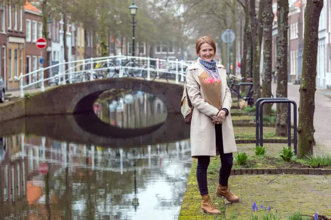 happy girl holding a bouquet of tulips standing on a street of Amsterdam. The Netherlands