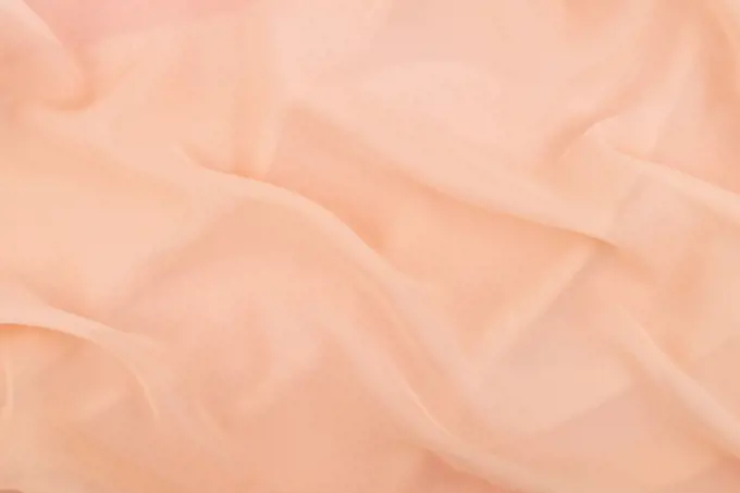 Peach coral soft chiffon fabric texture. Delicate folded cloth silk, organza, crepe chiffon background. Fashion elegant wedding background.