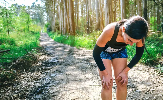 Tired young female athlete pausing at a trail competition. Female athlete pausing at a trail competition