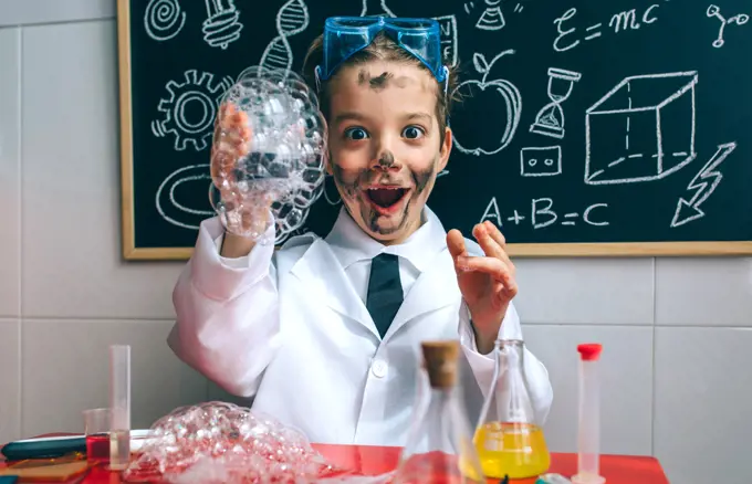 Funny happy boy dressed as chemist with dirty face after doing an experiment