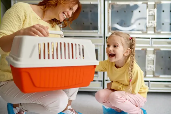 Joyful mother and girl child feeling happy after buying cat at shop. Woman and girl with cat carrier. Cheerful new pet owners. Joyful mother and girl child feeling happy after buying cat at shop