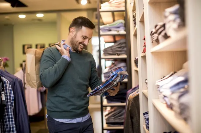 Handsome young man buying shirt in the store