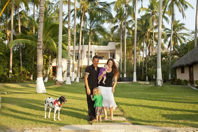 Portrait of young family in front of large house