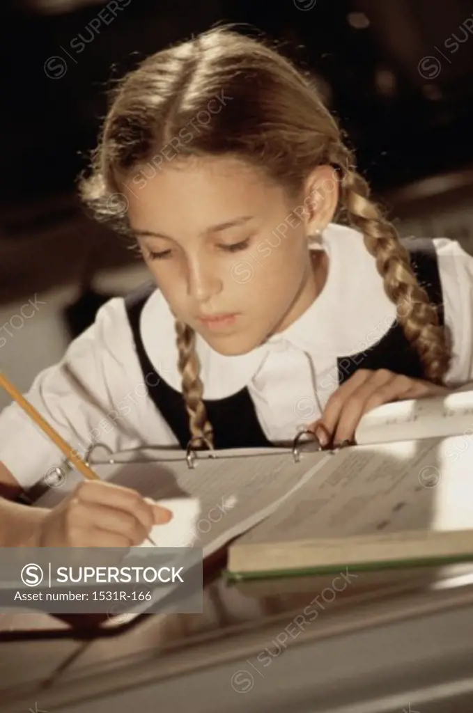 Girl writing in a book with a pencil