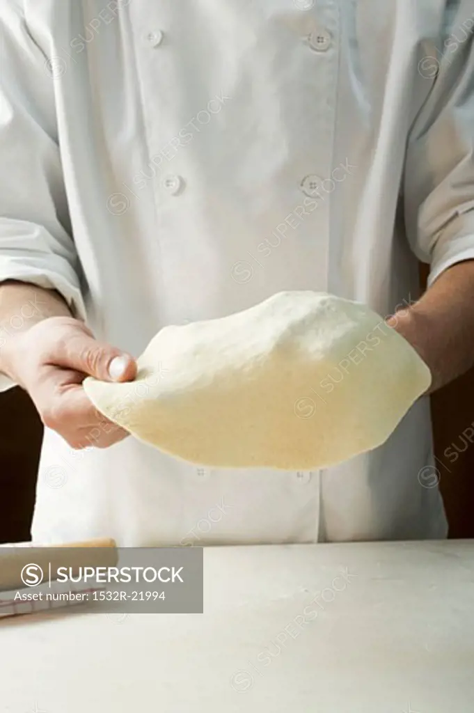 Shaping pizza dough by hand (stretching)