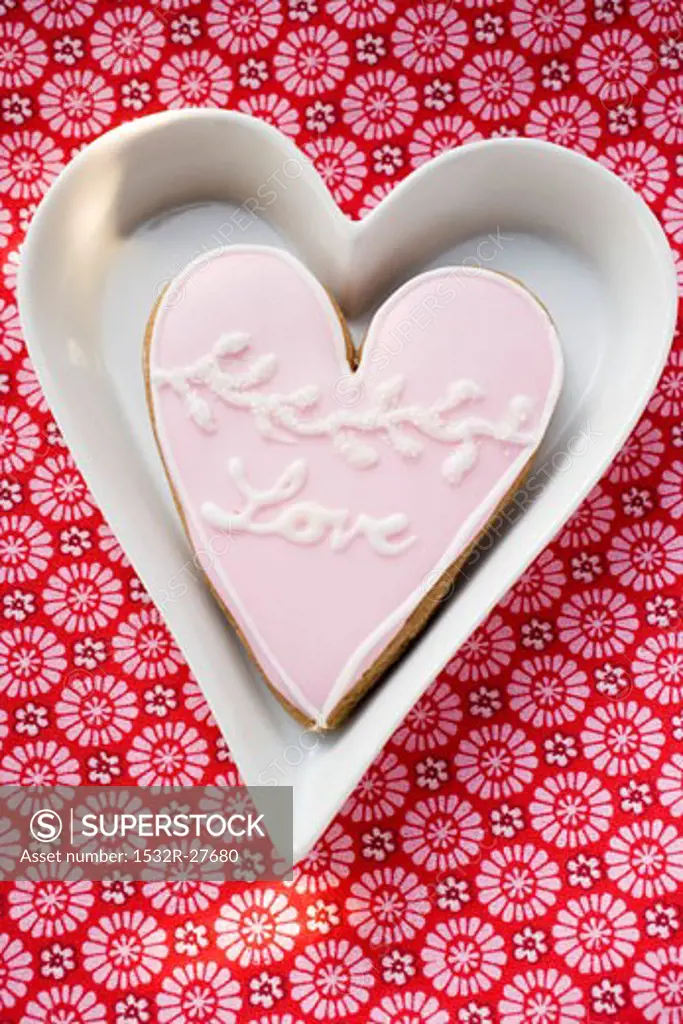 Heart-shaped biscuit with the word Love in white dish