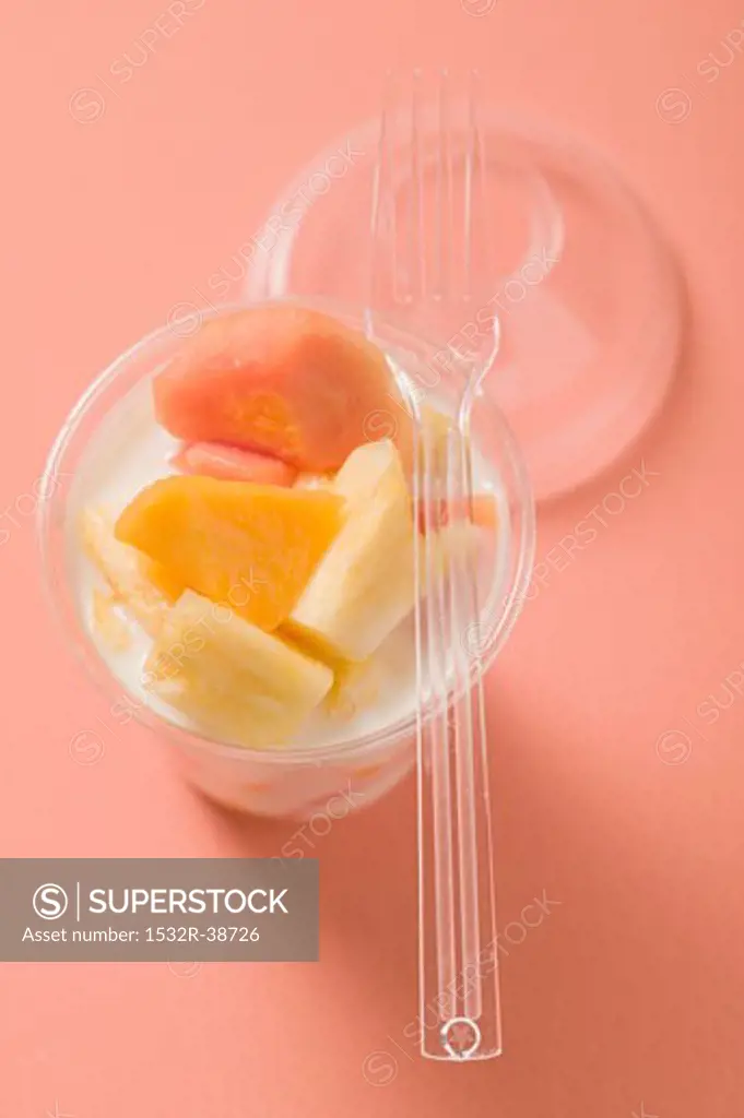 Yoghurt with fresh fruit in plastic pot, fork on pot