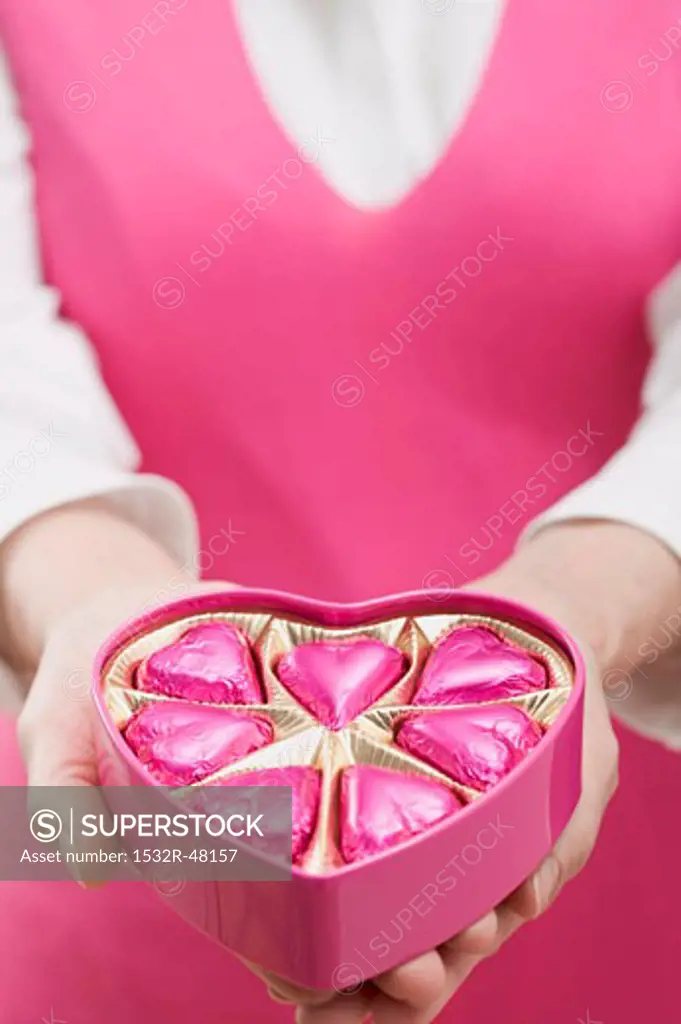 Woman holding box of heart-shaped chocolates