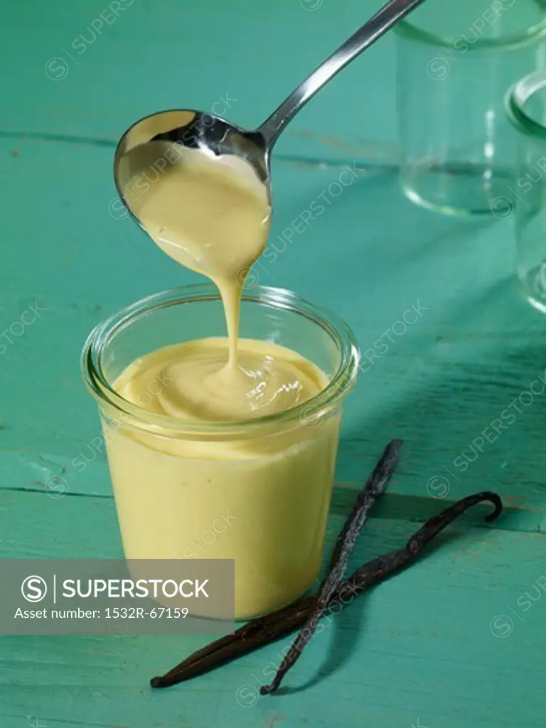 Using a ladle to fill a glass with vanilla pudding