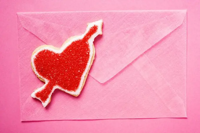 Pink envelope and red heart-shaped biscuit with arrow