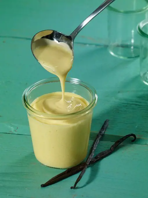 Using a ladle to fill a glass with vanilla pudding