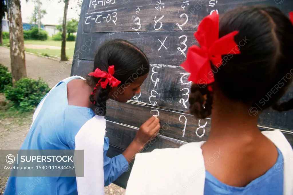 Rural school , girl writing on blackboard , Dehra Dun , Uttaranchal , India