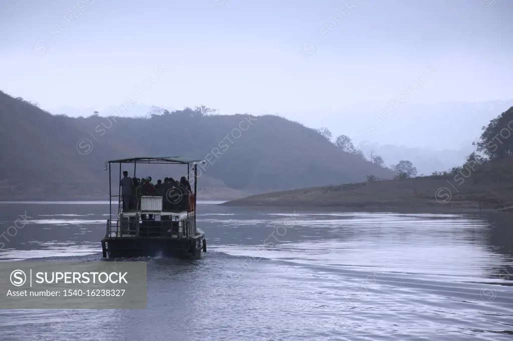 Early morning landscape of Periyar lake tourists on boat ride at Periyar lake ;  Periyar wildlife sanctuary ; Thekkady ; Kerala ; India