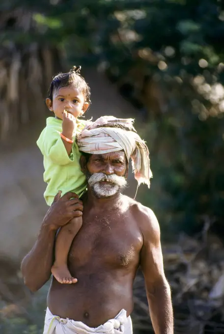 Granddaughter sitting on shoulder of grandfather , Tamil Nadu , India