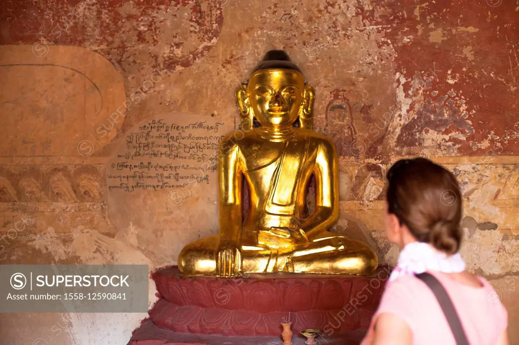 European tourist looking at golden Buddha statue in Bagan, Myanmar