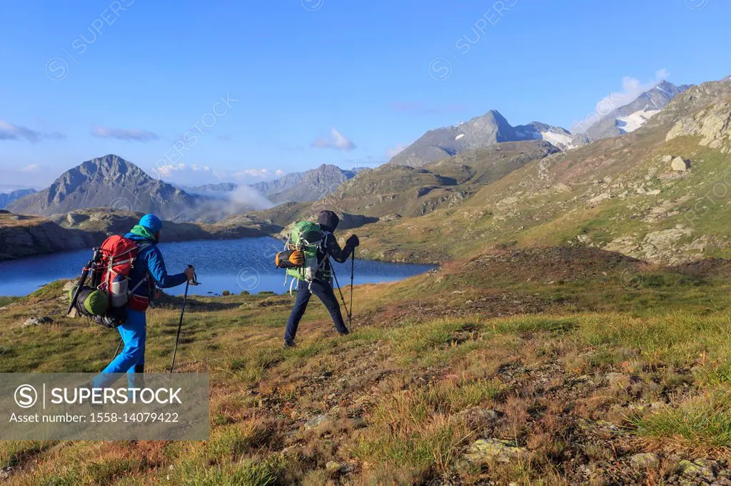 Hikers admire the peaks and the blue alpine lake Minor Valley High Valtellina Livigno Lombardy Italy Europe