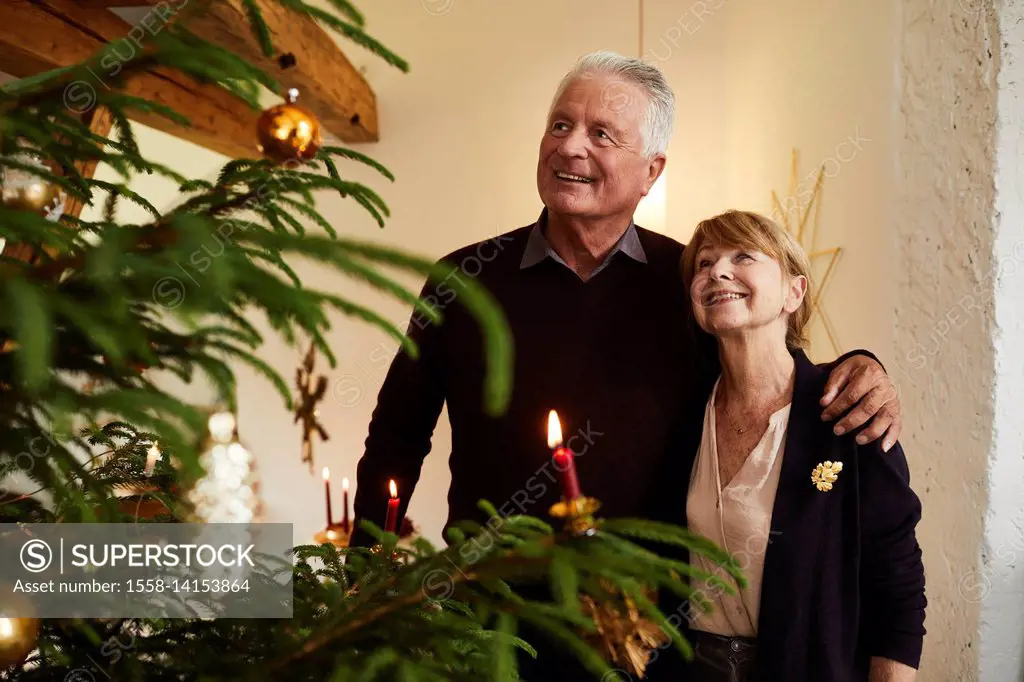 Senior couple in front of Christmas tree, half portrait