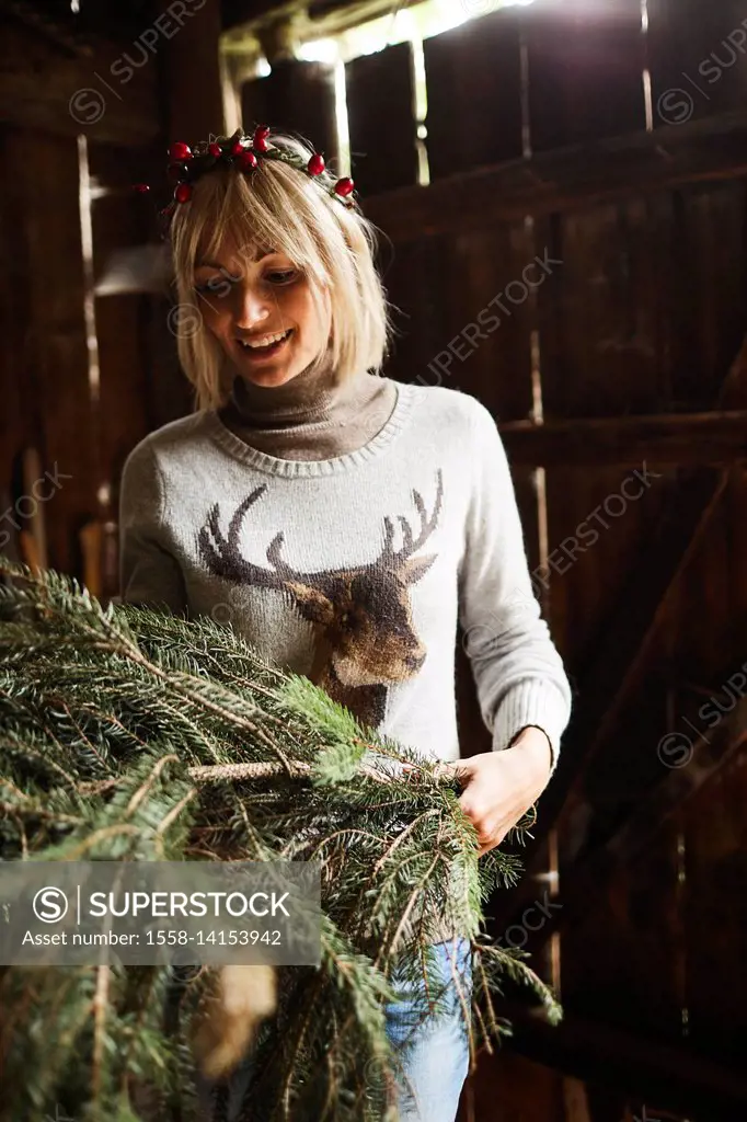 Blond woman, headdress, garland with rose hips, twigs of evergreens for decoration