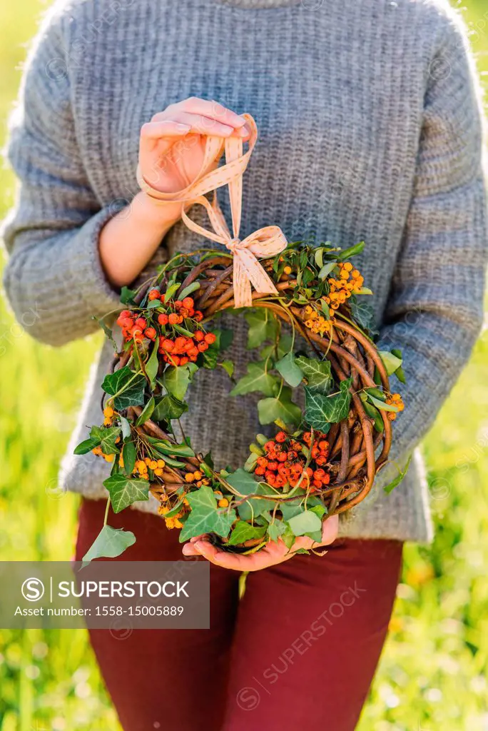 Woman holding autumnal wreath, detail,