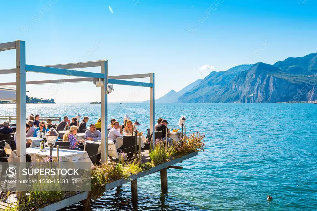 Malcesine, lake Garda, Verona province, Veneto, Italy. Tourists eating out in a restaurant on water.