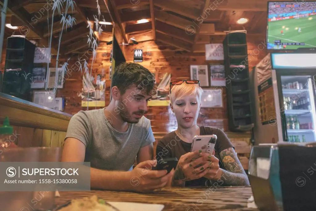 a tourist couple of husband and wife checking their phones on a restaurant