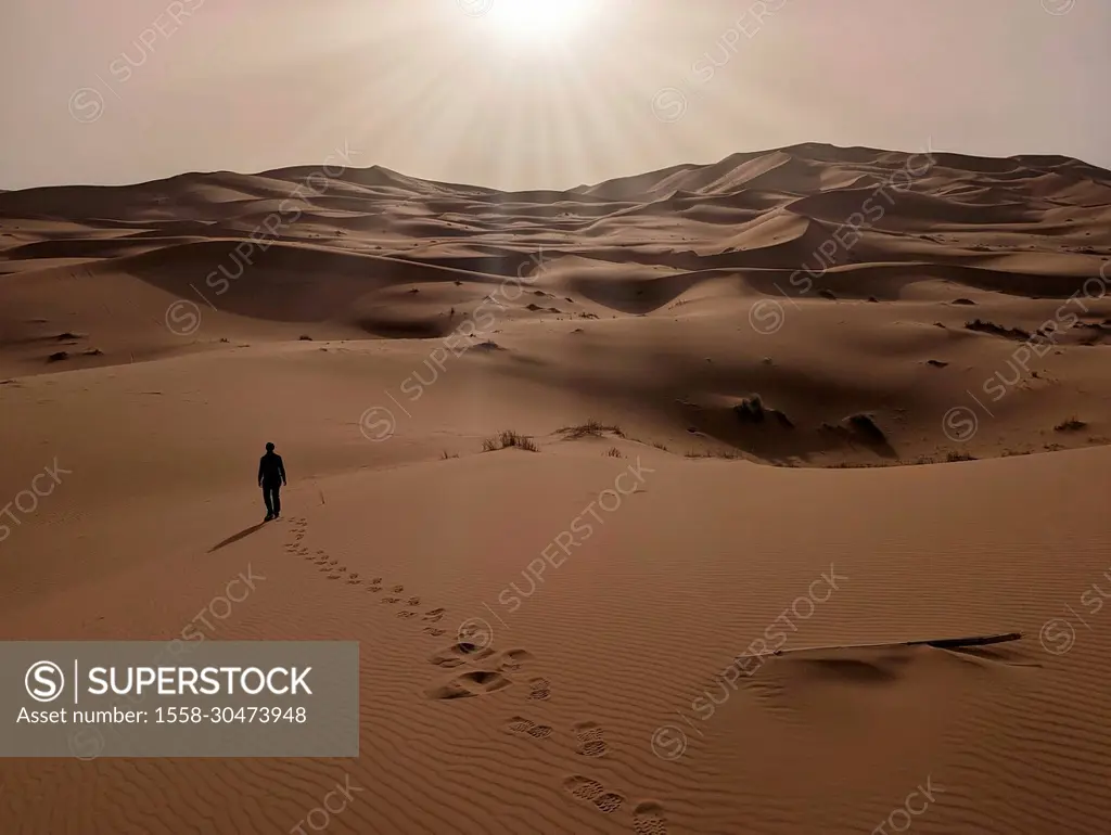 A person walking through the Erg Chebbi desert in the African Sahara, Moroccan desert